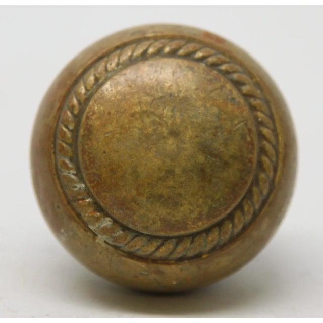 Traditional style bronze concentric door knob with a braided design. The manufacturer and date of creation is unknown....