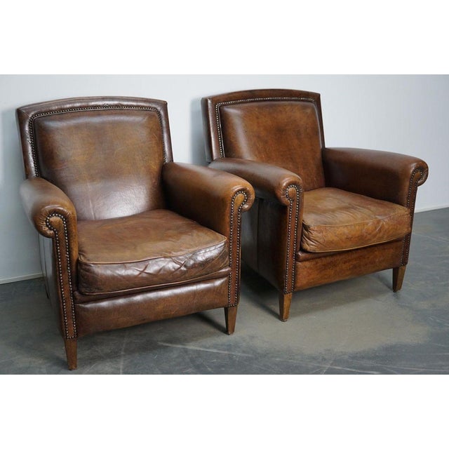 This pair of cognac-colored leather club chairs come from the Netherlands. They are upholstered with cognac-colored...