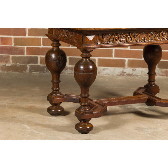 An English oak center table from the 19th century with star-shaped marquetry, carved apron, turned baluster legs and...