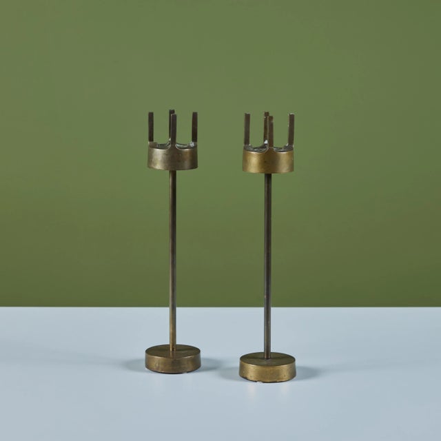 Pair of solid brass candlesticks. The pair of beautifully patinated candlesticks feature thick round bases with narrow...