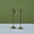 Pair of solid brass candlesticks. The pair of beautifully patinated candlesticks feature thick round bases with narrow...