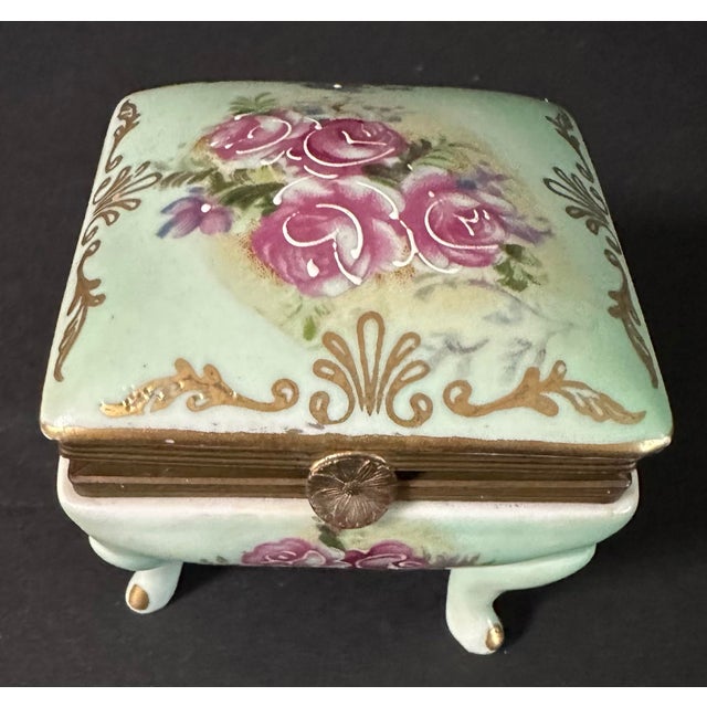 Vintage porcelain jewelry/trinket box. Hand painted light green in color with pink & green floral motif and gold...