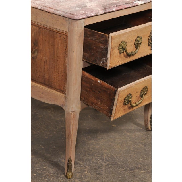 A French raised two-drawer side chest, with original marble top, from the 18th century. This antique smaller-sized commode...