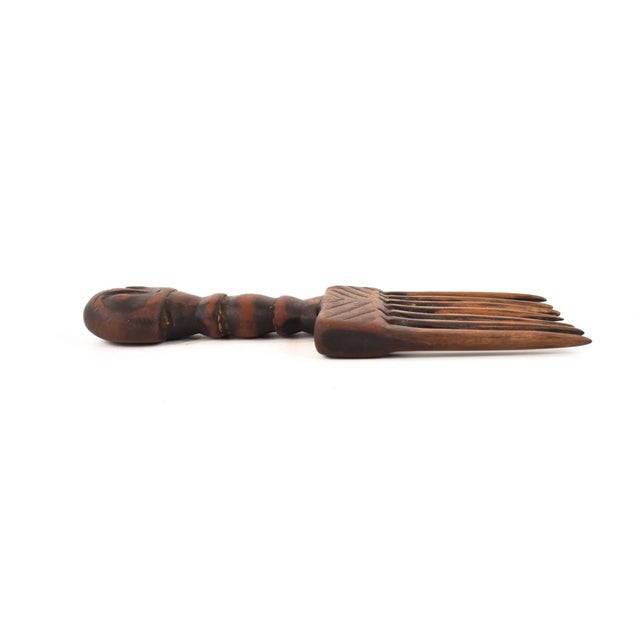A wonderful comb carved out of wood with a stylized human figure on the handle and decorated with geometric carvings. The...
