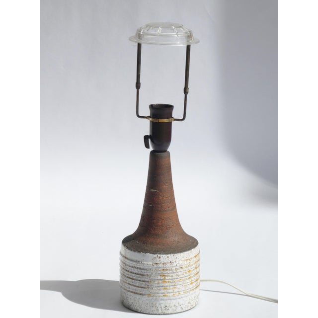 A vintage modern lamp made in Denmark, stamped on the bottom. The beautiful lamp has an earthy ceramic base with a glazed...