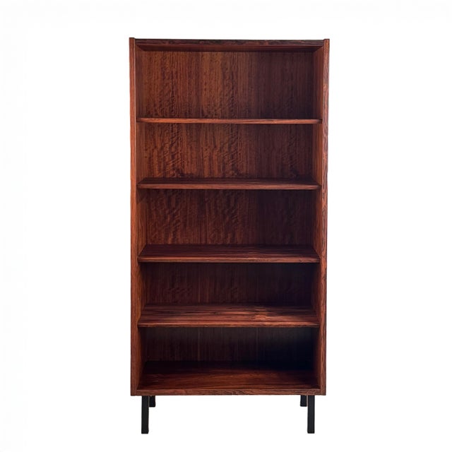 Vertical bookcase crafted in Brazilian rosewood with adjustable shelves and black steel legs. Stunning rosewood grain...