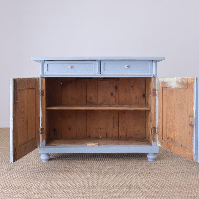 A charming antique pine cupboard with beautiful pale blue paint and plenty of character throughout. The painted finish...