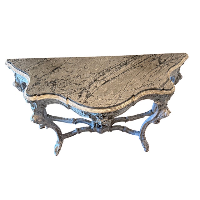Italian Rococo style console table with shaped inset marble top over a carved wood base. The frame features a serpentine...