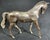 A brass horse sculpture in a walking pose with a smooth, polished body in a warm bronze tone reddish-brown patina or...