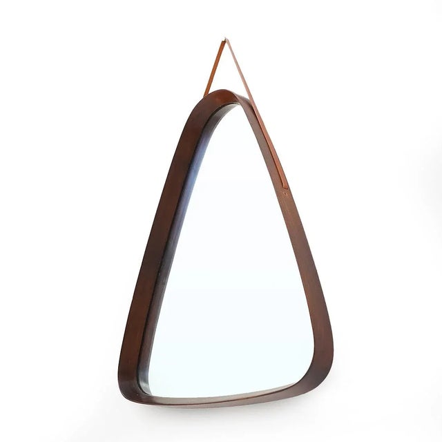 Italian made wall mirror produced in the 1960s. Frame in turned and curved teak. Ground mirror. Leather strap fixed inside...