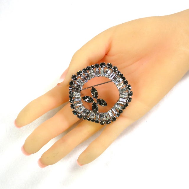 Vintage 1950s silver-plated crystal brooch, unsigned but recognizably Weiss. A circular undulating ribbon design w/ an...