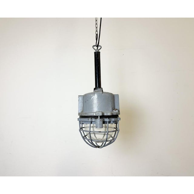 Dark grey industrial lamp with massive protective glass bulb made by elba in romania during the 1970s.it features a cast...