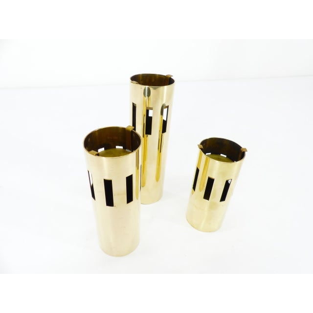 Set of three Scandinavian tealight holders in modernist style, in polished golden brass. Each tealight holder has a...