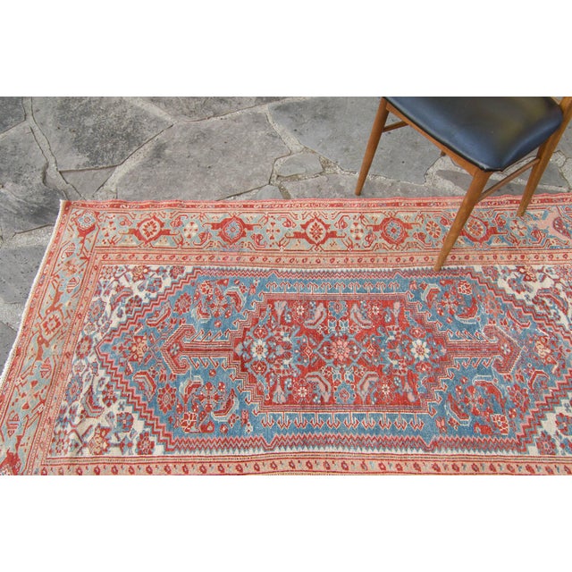 This small hand-knotted rug highlights an intricately detailed medallion with a floral motif throughout the rug. Red and...
