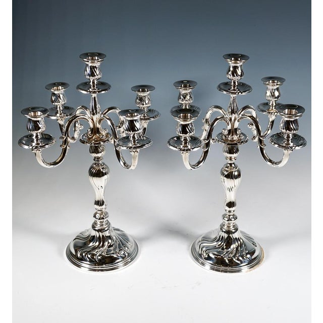 Two elegant five-candle holders on a stepped, curved base with four triple-pleated curving pleats that continue up the...