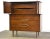A mid century modern walnut tall dresser with polished brass drawer pulls and stretchers designed by Helen Hobey for...