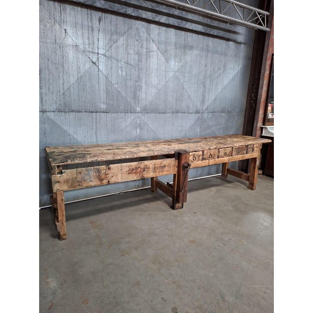 Impressive 325 cm long industrial workbench with a solid, well-used wooden top and original bench vice. The worktop...