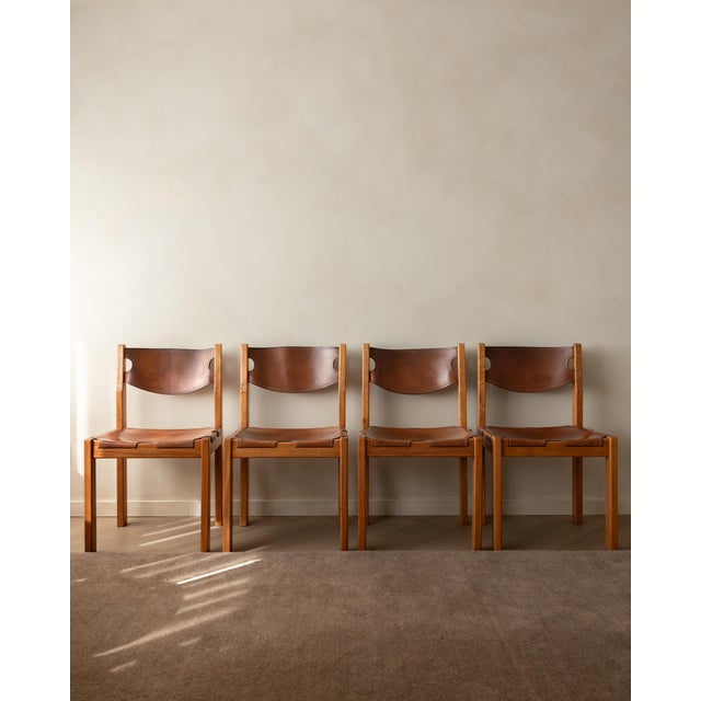 A vintage set of four french brutalist dining chairs in solid elm and cognac leather, made by maison regain in france...