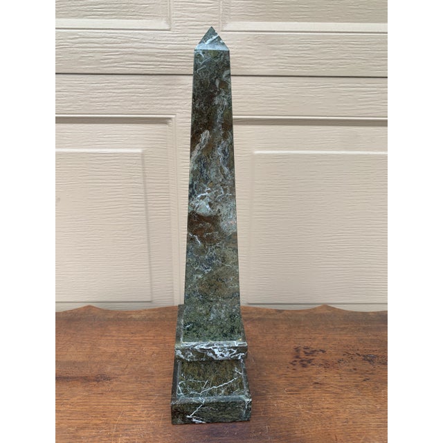 A beautifully proportioned marble obelisk in richly veined shades of black, brown, and gray. The sculptural silhouette and...
