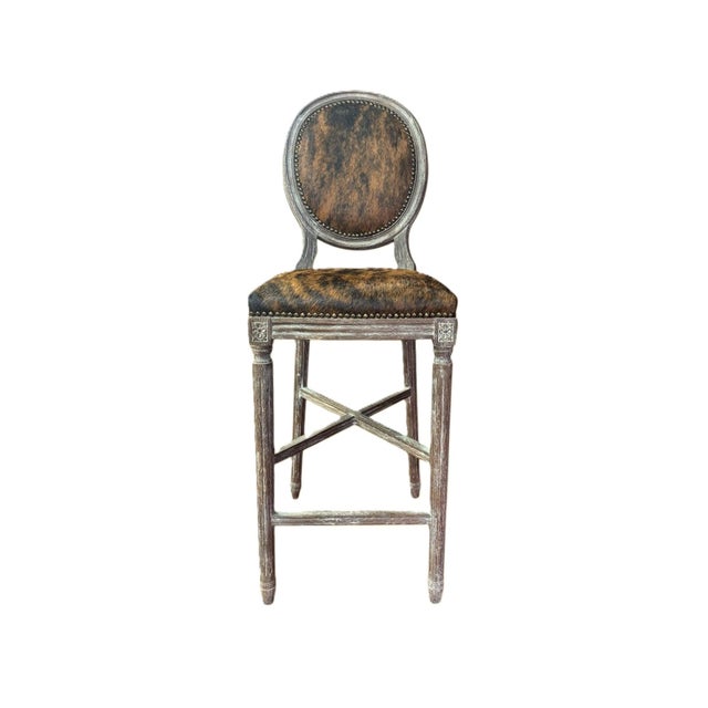Elevate your space with this elegant bar stool, featuring a sturdy oak wood frame paired with a luxurious cowhide...
