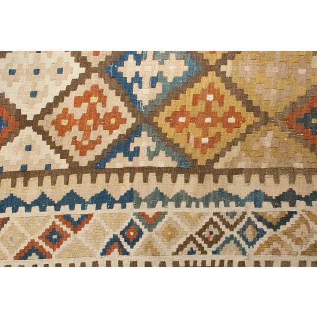 An early 20th Century Persian Shiraz Kilim runner with all-over multi-colored diamond and geometric pattern surrounded by...