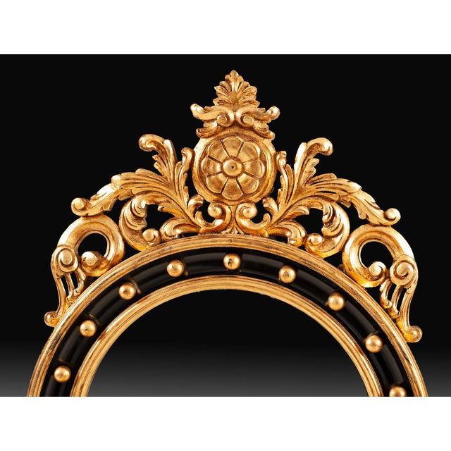 Handcrafted in Italy, this oval mirror features beveled glass within a black frame accented by gold detailing. Carved...
