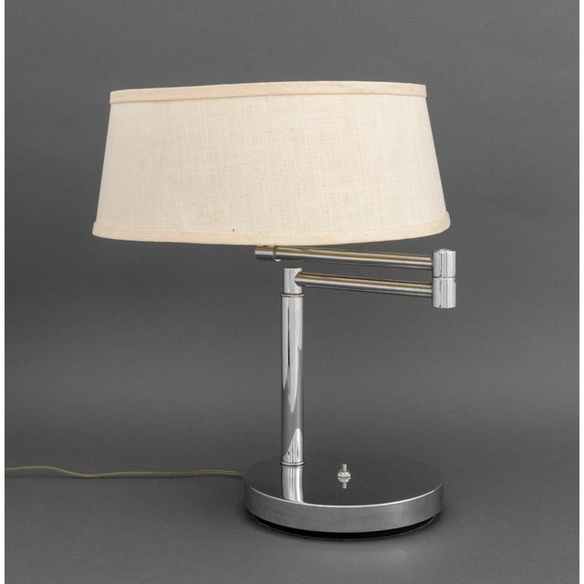 Mid-Century Modern Chrome Swing-Arm Table Lamp, with two bulb fittings and an Artemis Studios white linen shade. Arm fully...