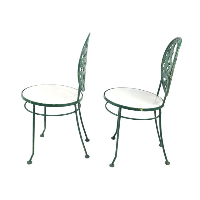 A distinctive pair of vintage metal chairs showcasing mid-century modern craftsmanship. Each features a circular backrest...