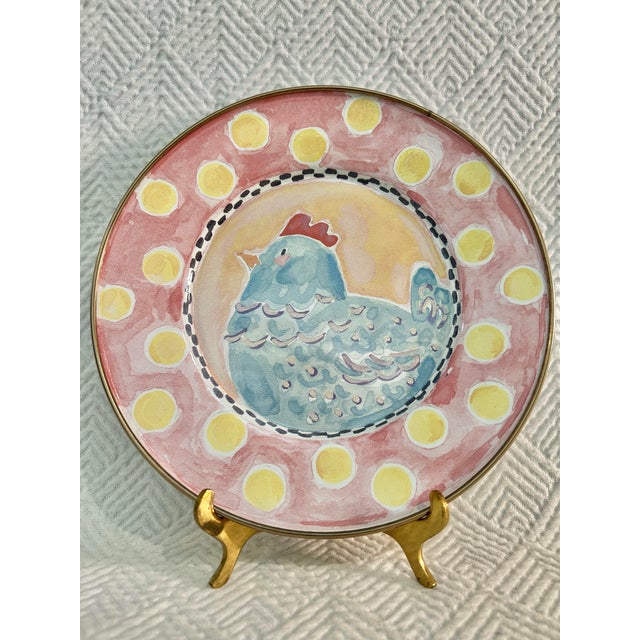 This “Spring Chicken” MacKenzie-Child’s plate and cup set features a playful blue chicken motif against a soft watercolor...
