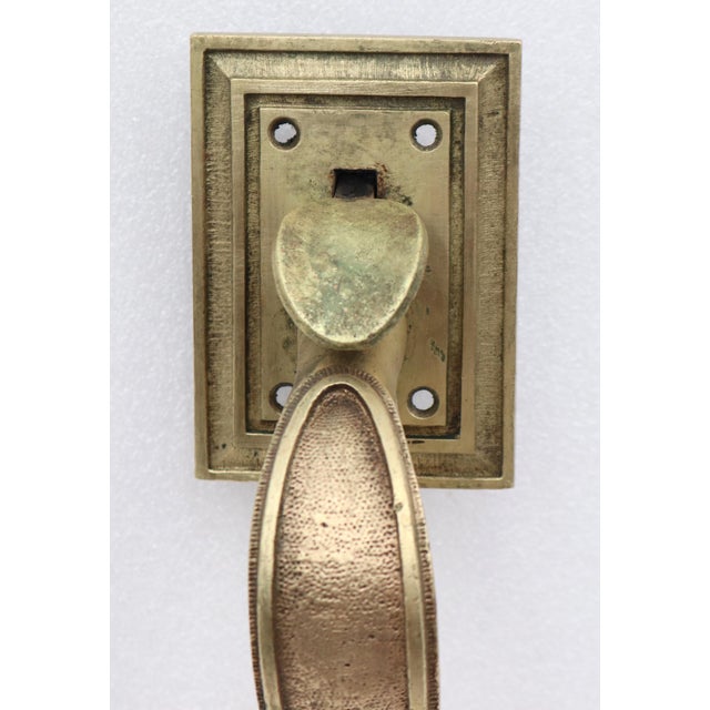 Vintage polished brass thumb latch door pull with a curved shaped handle and square plates. The original mounting screws...