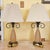 A sculptural pair of table lamps featuring elongated teardrop frosted glass bodies in a warm amber-orange tone, accented...