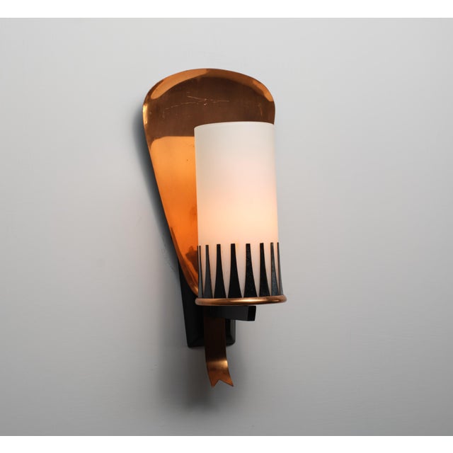 Wall-mounted sconce designed and produced in italy around 1950. the structure combines a curved bronze reflector, a black-...