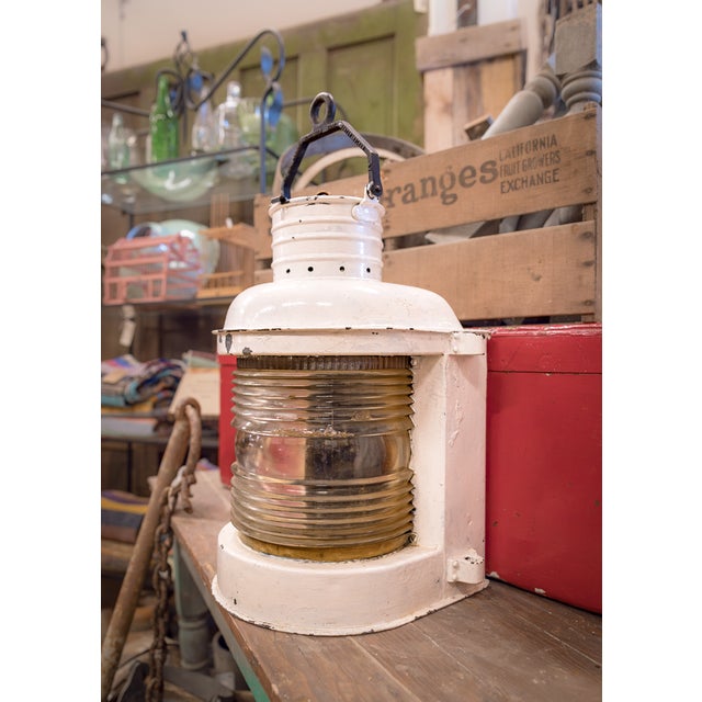 An early 1900s navigation ship lantern featuring a glass fresnel lens and steel metal frame.