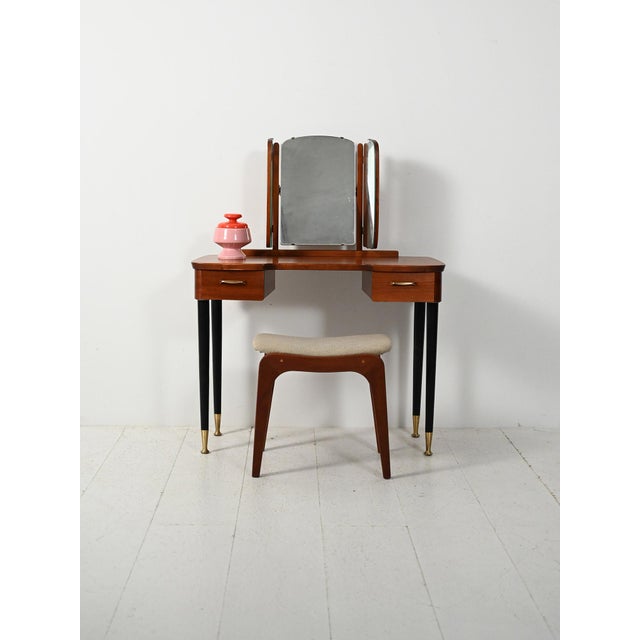 Scandinavian teak dressing table with tapered black legs, two drawers, and a trilobed mirror with a reclining centerpiece....