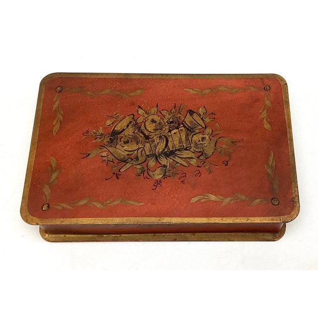 This charming antique toleware box features a rich red salmon ground accented with gold decoration and a classic hinged...