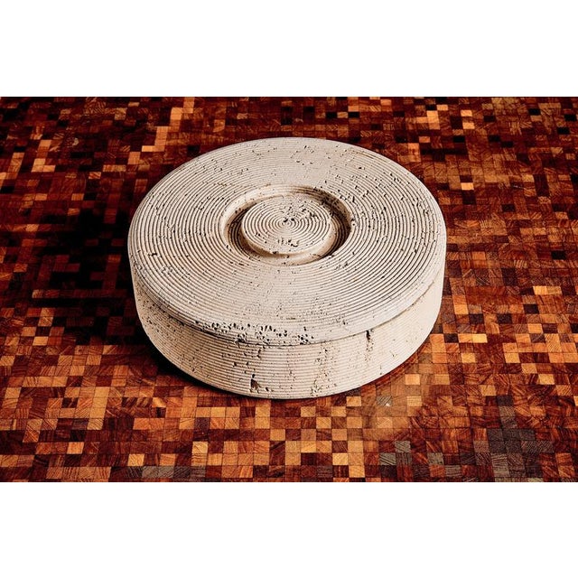 Round lidded box in carved travertine. Sculptural container with concentric carved rings and natural travertine pitting,...