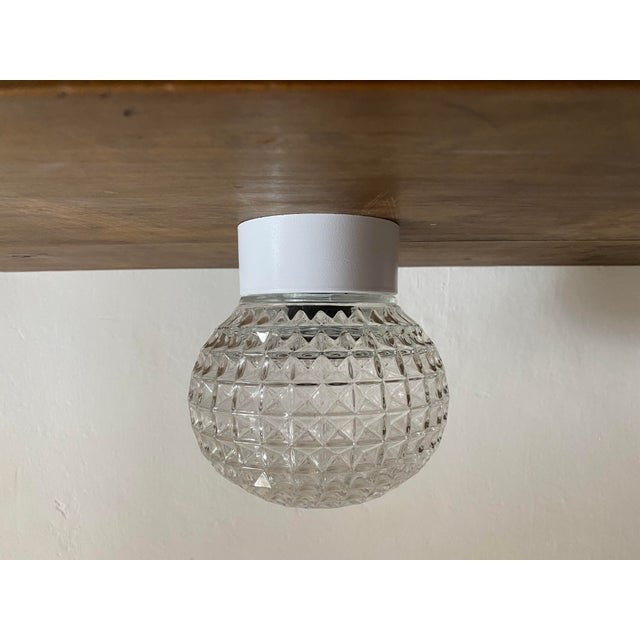 Vintage flush mount ceiling light dating from the 1970s, featuring a thick clear pressed glass shade with a distinctive...