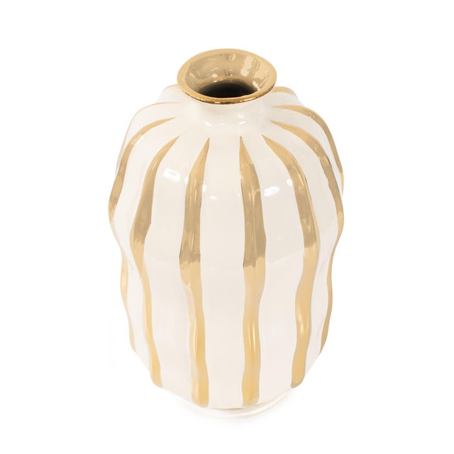 Finished in a smooth cream glaze and detailed with striking metallic gold accents, this vase brings a modern sense of...
