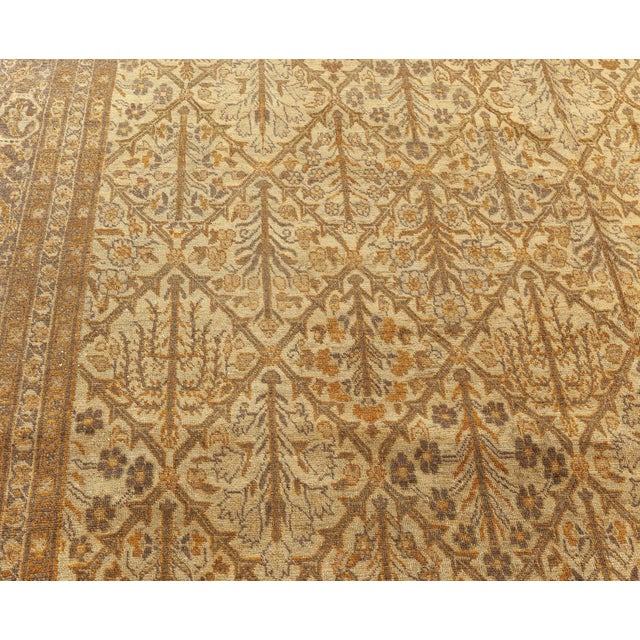 An early 20th century Tabriz rug, the sand field with an allover beige lozenge lattice containing flowering branches...