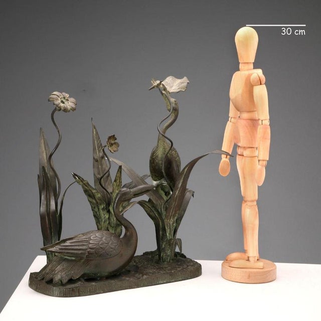 Bronze patinated metal planter composed of three cylindrical single-flower vases hidden among the leaves of a marshy...