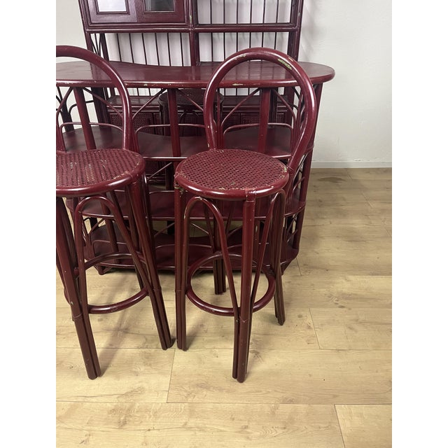 Bamboo, wicker, and glass bar unit, consisting of a wall unit, a backless stool, two stools with backrests, and a burgundy...