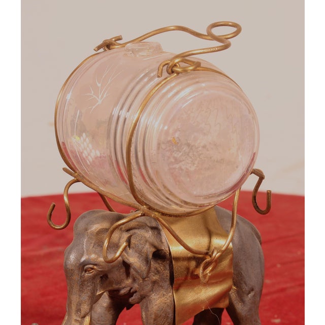 A charming late 19th-century liquor cabinet depicting an elephant with its trunk raised, resting on a beautifully...