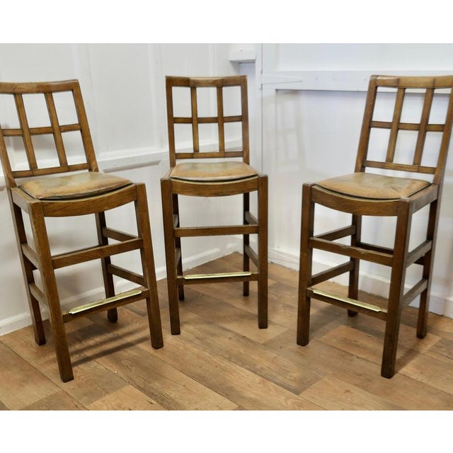 A Rare Trio of Arts and Crafts High Bar Stools, in Golden Oak A trio of early 20th century oak lattice back dining chairs,...
