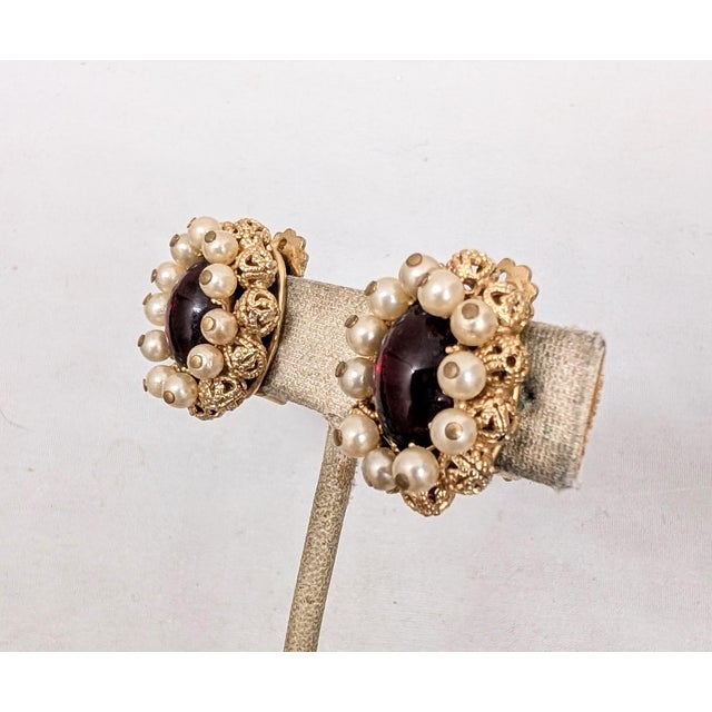 1950s goldtone oval cabochon faux-garnet with faux pearl dangles surround and filigree goldtone beads behind the faux-...
