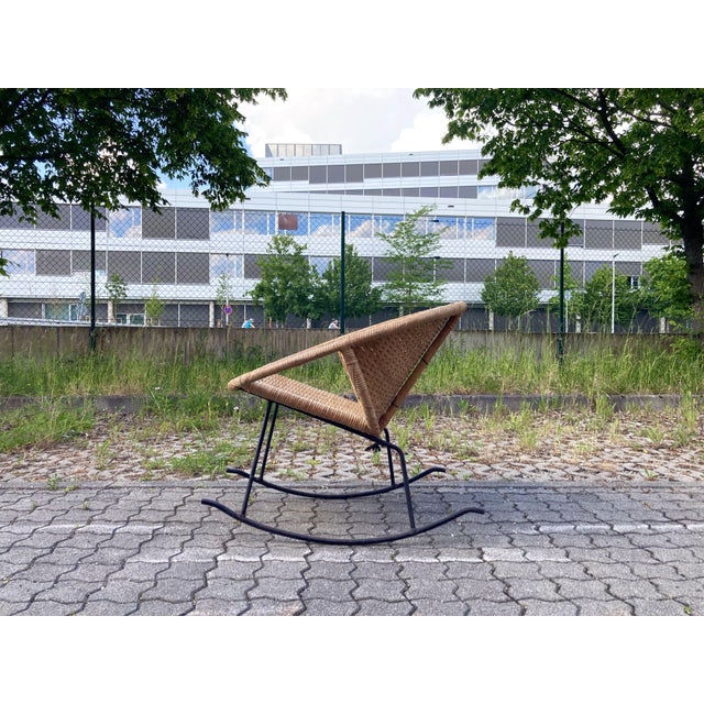 Elegant modernist rocking chair from the 1960s, handcrafted in woven cane and wicker. The organic, sculptural seat is...