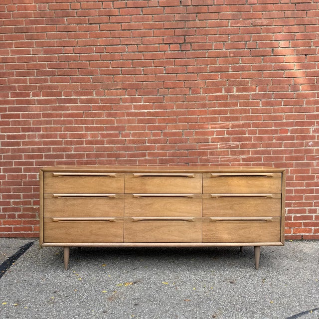 This handsome mid-century modern dresser features a clean, streamlined silhouette accented by sculpted integrated drawer...