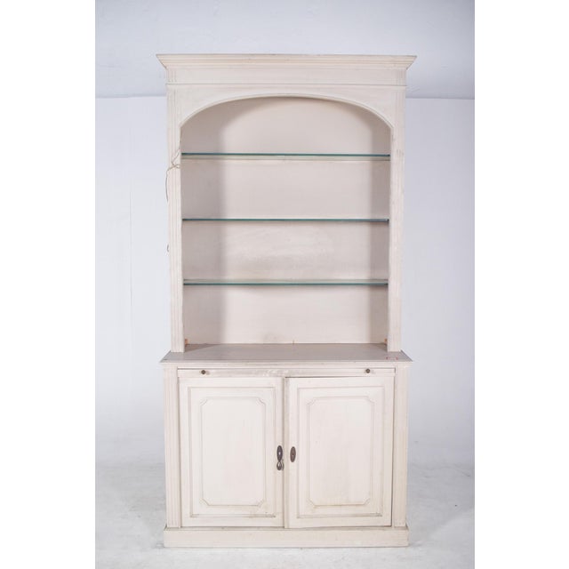 Bookcase with two doors, painted white. Composed of two parts, a lower part with a double-door cupboard and an upper part...