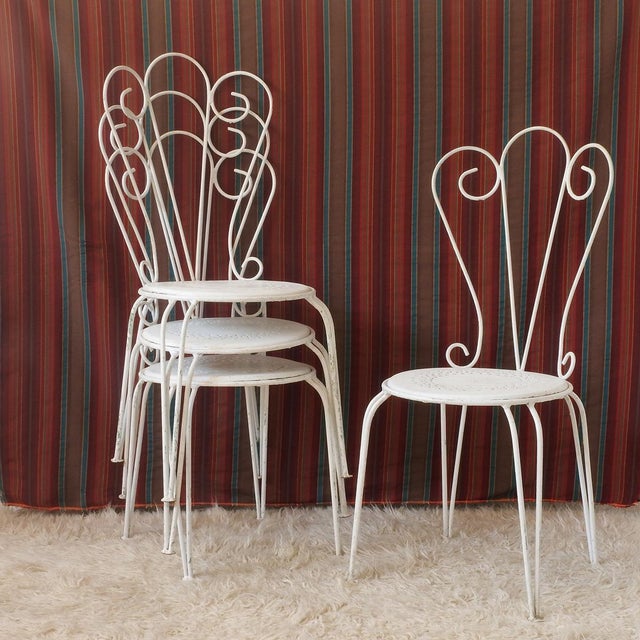 Four Mid-Century wrought iron chairs, painted white. Romantic in style, they are ideal for a patio or porch. Jean-Michel...