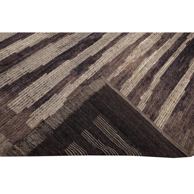 Beautiful Moroccan style handmade wool rug with a beige field. This Modern rug has brown accents and beige-brown braid...