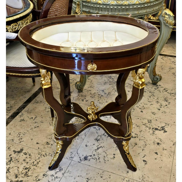 Add a touch of refined French elegance with this distinctive oval side table, featuring a rich, high-gloss wood finish, an...